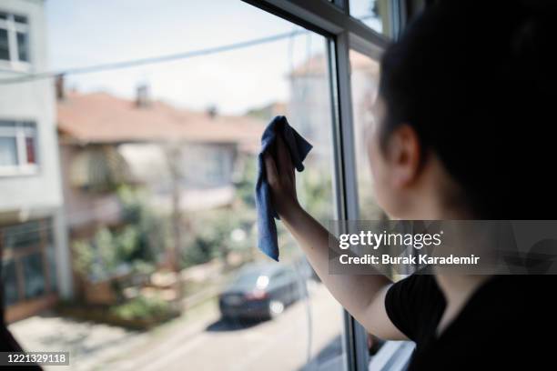 yong woman cleaning window - cameriera foto e immagini stock