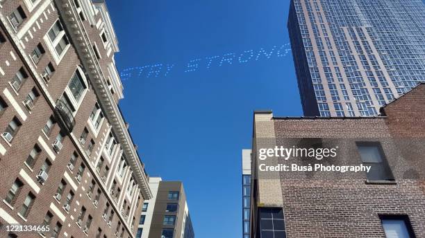 imaginary sky writing (airplane smoke trail writing) with text "stay strong" in the sky (manipulated image) - skywriting stock pictures, royalty-free photos & images