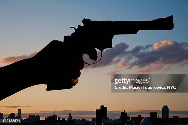 hand with gun against evening sky - teilabschnitt stock-fotos und bilder