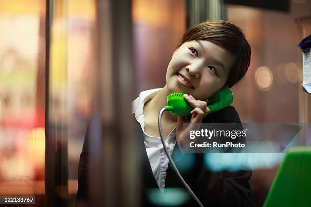 young businesswoman talking on pay phone,evening - pay phone stock pictures, royalty-free photos & images