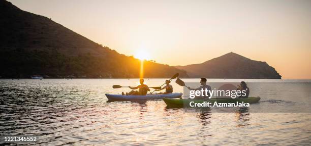 tandem kayakers paddling in mediterranean at sunrise - sea kayak stock pictures, royalty-free photos & images