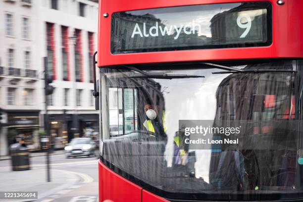 Transport for London bus driver wears a protective face mask as he drives the city centre on April 27, 2020 in London, England. TfL has announced...