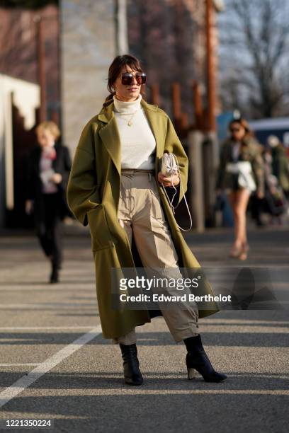 Carlotta Rubaltelli wears sunglasses, a white wool pullover, a green long coat, a golden necklace, a bag, beige pants, black leather shoes, outside...