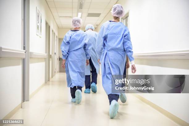 squadra di personale medico in dispositivi di protezione individuale che cammina nel corridoio ospedaliero - corridoio caratteristica di una costruzione foto e immagini stock