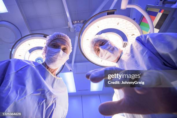 senior surgeons standing over patient in operating room - personal perspective doctor stock pictures, royalty-free photos & images