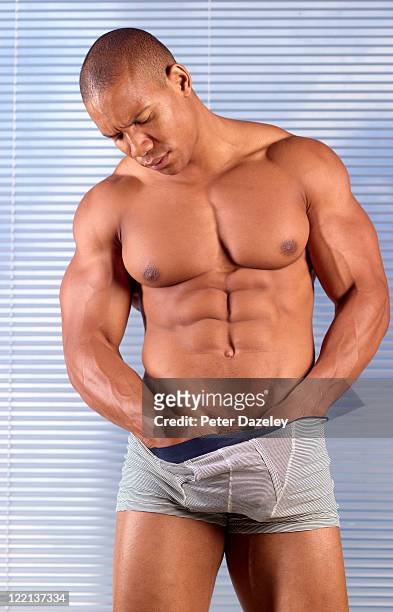 muscular man checking for testicular cancer - dysfonctionnement de l'érection photos et images de collection