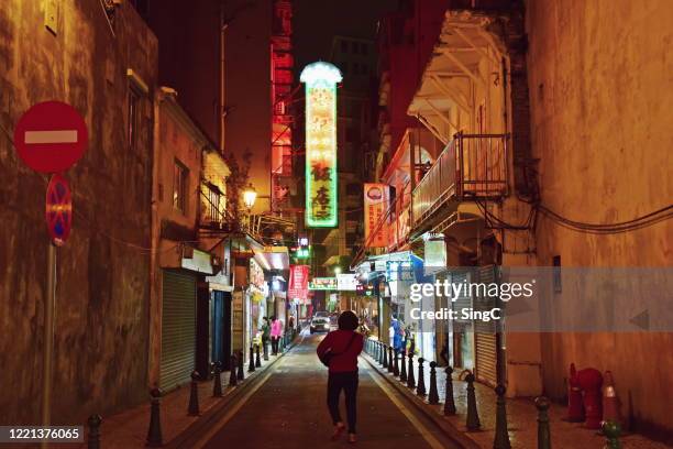 a woman walking towards a street of neon lights in macau - macao stock-fotos und bilder