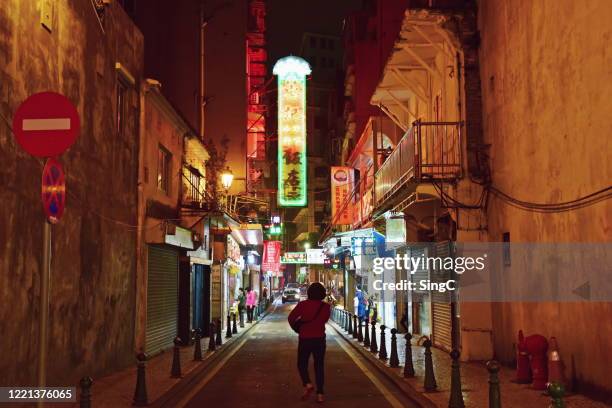 a woman walking towards a street of neon lights in macau - macao fotografías e imágenes de stock