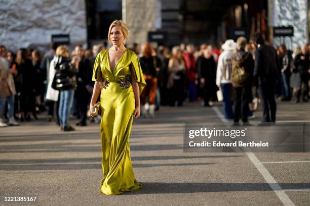 Guest wears a shiny green/yellow lustrous long v-neck low-neck silky dress with floral colorful glittering embroidery, a bag, outside Alberta...