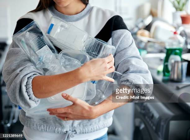 woman holding armful of used plastic containers in kitchen - plastic stock pictures, royalty-free photos & images