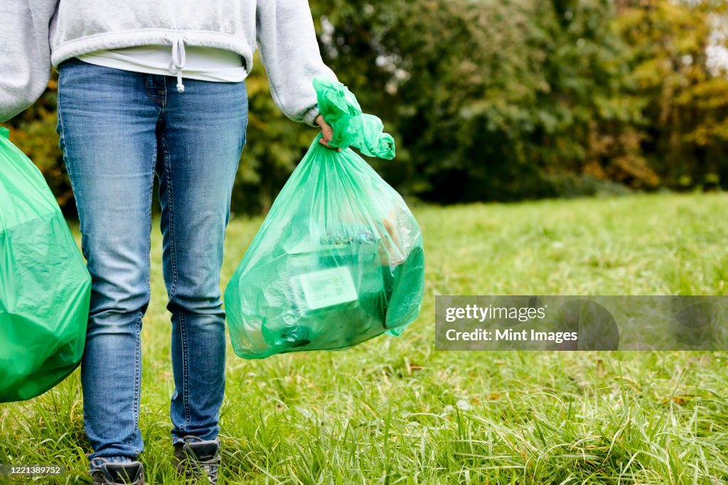 Woman stuffing soft waste plastics into large plastic bottle to make an ecobrick for use as a building block