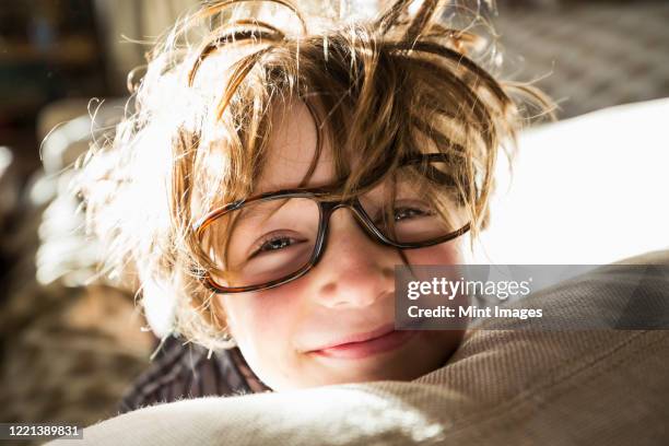 portrait of a six year old boy with disheveled hair and oversized glasses waking up.  bedhead hair. - visage caché par les cheveux photos et images de collection