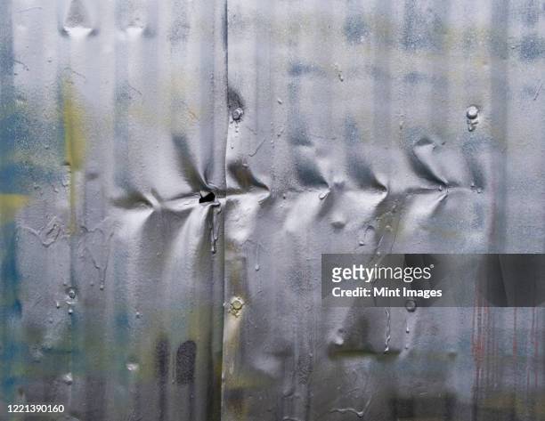 row of indentation marks on silver spray painted metal wall, close up - abollado fotografías e imágenes de stock