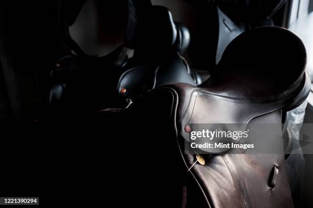 close up of a selection of black and brown leather saddles. - leather craft stock pictures, royalty-free photos & images