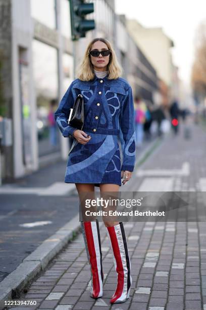 Candela Novembre wears sunglasses, a white turtleneck top, a black bag, a blue denim short dress with buttons, red and white leather striped boots,...