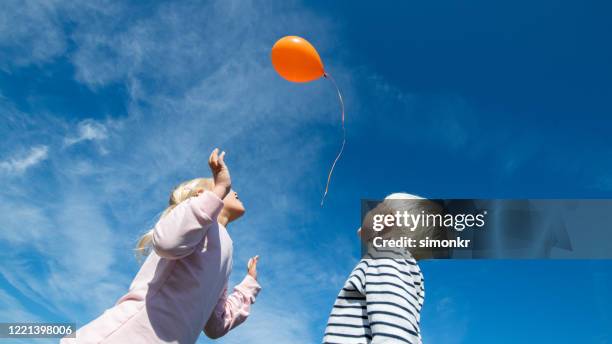 jonge geitjes die ballon in blauwe hemel vrijgeven - only kids at sky stockfoto's en -beelden