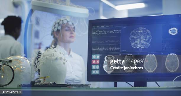 実験室で脳波スキャンヘッドセットを調べる科学者。 - brain wave ストックフォトと画像