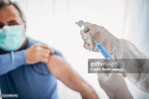 先輩男性はcovid-19コロナウイルスワクチンを受け取ろうとしています - injecting ストックフォトと画像
