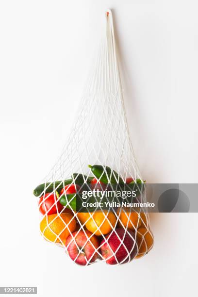 fruits and vegetables in a mesh bag. cucumbers and tomatoes and apples and oranges in a white ecological bag. eco zero waste concept, no plastic. - tulle photos et images de collection