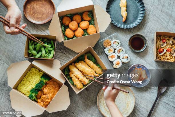 sharing assorted takeaway meal at home - eating sushi stock-fotos und bilder