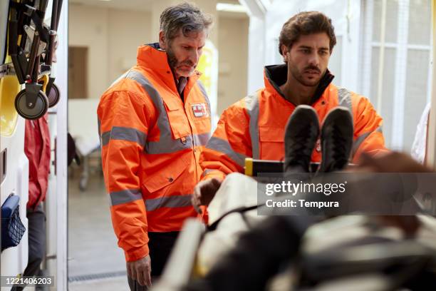 el personal de la ambulancia asegura una camilla del hospital dentro de una ambulancia. - material reflector de seguridad fotografías e imágenes de stock
