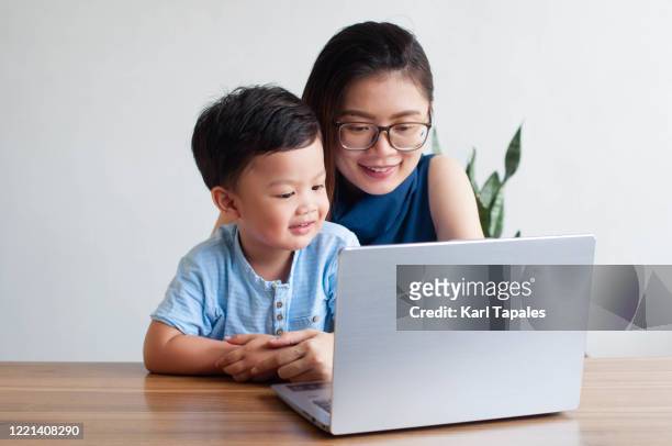 a young southeast asian mother is homeschooling his son using a laptop - philippines family 個照片及圖片檔