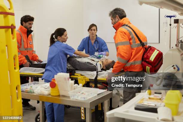 enfermeras y trabajadores de emergencia que transfieren a un paciente de la camilla del hospital a la camilla - vista general fotografías e imágenes de stock