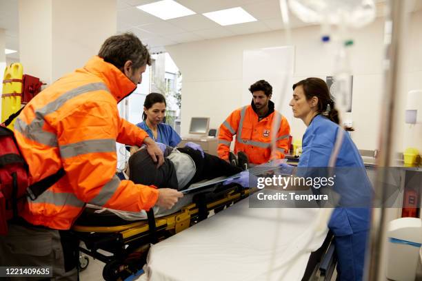 ambulance staff and nurses transferring a patient from the hospital gurney to the stretcher - ambulance arrival stock pictures, royalty-free photos & images