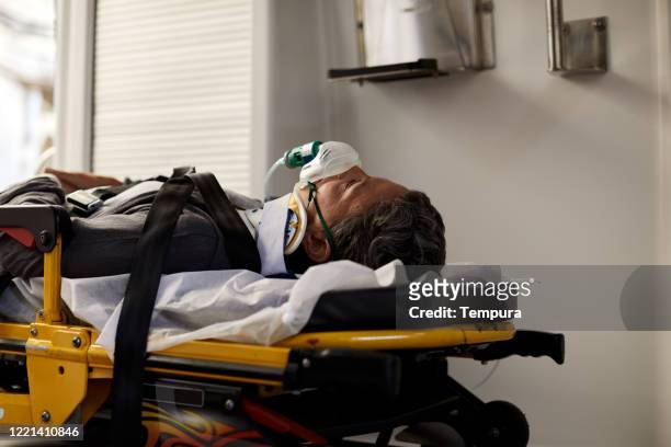 patient lying down on a hospital gurney inside and ambulance. - hospital gurney stock pictures, royalty-free photos & images