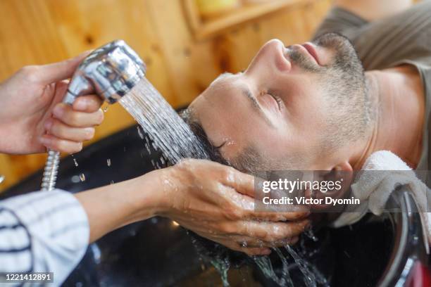 shooting in the barbershop. asian barber cuts white man - mens hair model stock pictures, royalty-free photos & images