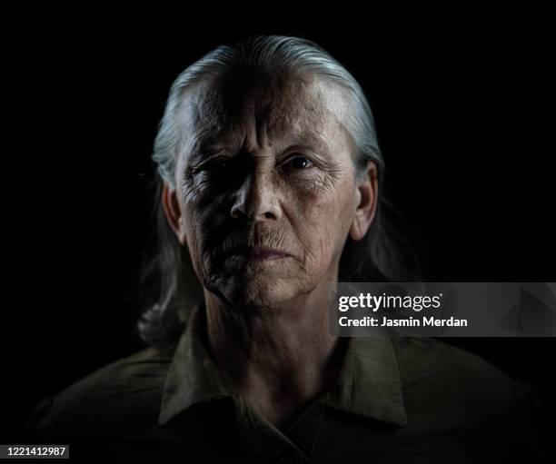 fine art portrait in dark of senior woman - kontrastreich stock-fotos und bilder