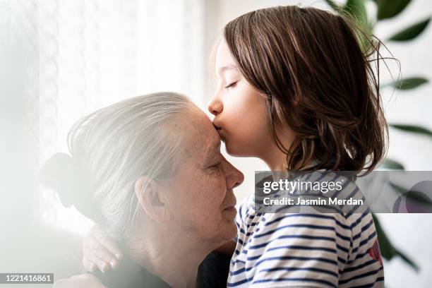 lovely little boy kissing his grandmother - kissing kids stockfoto's en -beelden