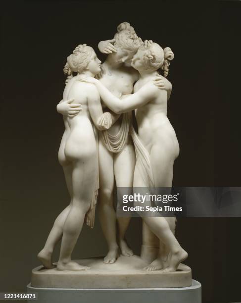 The Three Graces, They stand on a plinth and have their arms around each other. A drapery connects the three naked female figures. On the plinth...