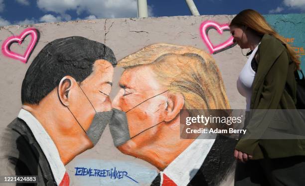 Pedestrian passes graffiti of Communist Party of China General Secretary Xi Jinping and U.S. President Donald Trump kissing each other while wearing...