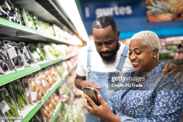 paar kauft im supermarkt mit handy - couple in supermarket stock-fotos und bilder