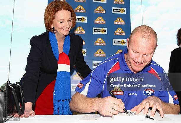 Prime Minister Julia Gillard looks on as Barry Hall signs his book at the official launch of his new book 'Pulling No Punches' at Whitten Oval on...