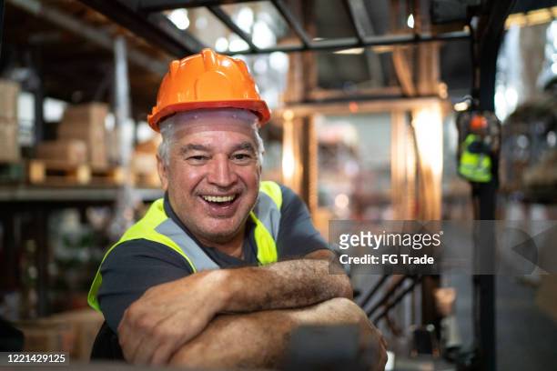 portrait of senior male worker driving forklift in warehouse - ware house worker forklift stock pictures, royalty-free photos & images