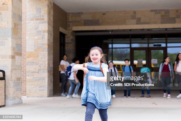 independent girl with down syndrome leaves school building - last day of school stock pictures, royalty-free photos & images