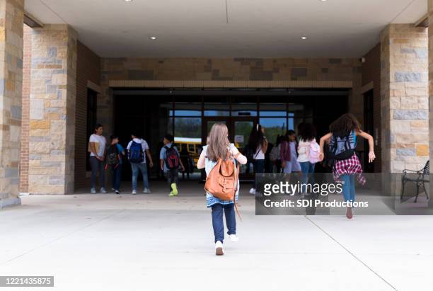 group of student walking into school building - entering stock pictures, royalty-free photos & images