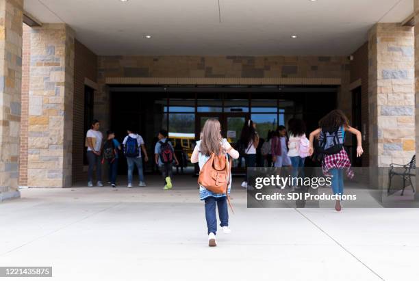 group of student walking into school building - walking to school stock pictures, royalty-free photos & images