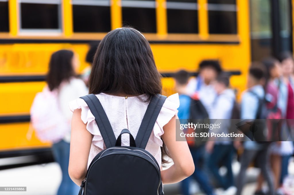 Rückansicht des Mädchens zu Fuß zum Schulbus