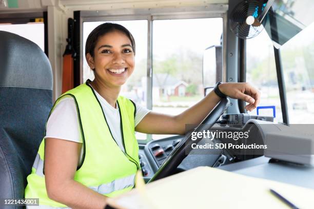 assis derrière le volant, le conducteur sourit pour la caméra - school bus stock photos et images de collection