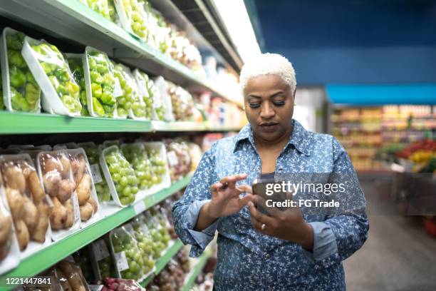 frau kauft im supermarkt mit handy - chubby man shopping stock-fotos und bilder