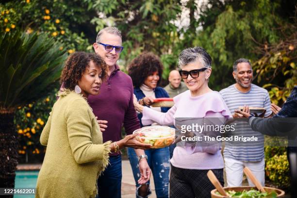 smiling friends walking into backyard dinner party with food - the party arrivals stock pictures, royalty-free photos & images