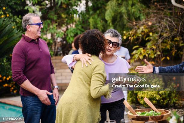 mature friends embracing at backyard dinner party - day california arrivals stockfoto's en -beelden