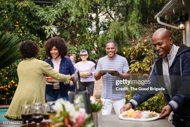 mature couple welcoming guests for dinner party - day celebration dinner arrivals stockfoto's en -beelden