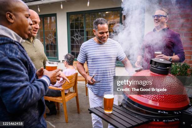 mature men standing by barbecue grill talking - sólo con adultos fotografías e imágenes de stock