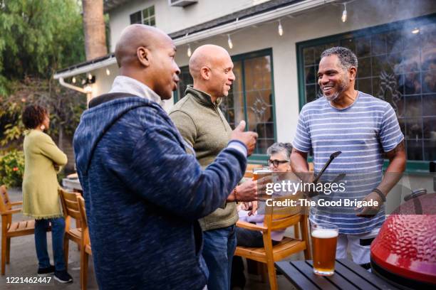 mature male friends enjoying barbecue party - friends chatting mature foto e immagini stock