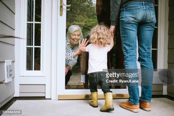 little girl visits grandparents through window - quarantine stock pictures, royalty-free photos & images