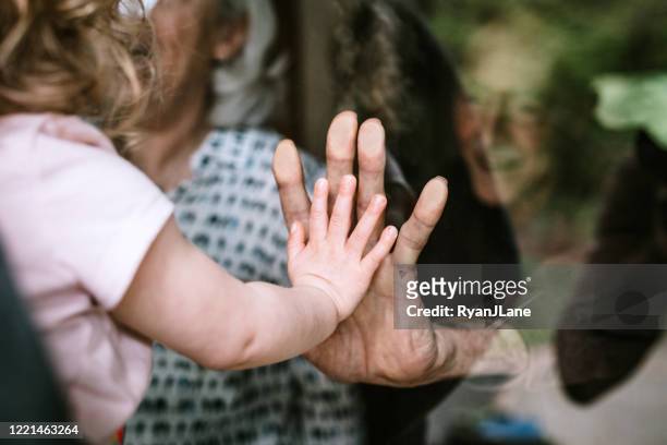 little girl visits grandparents through window - togetherness stock pictures, royalty-free photos & images